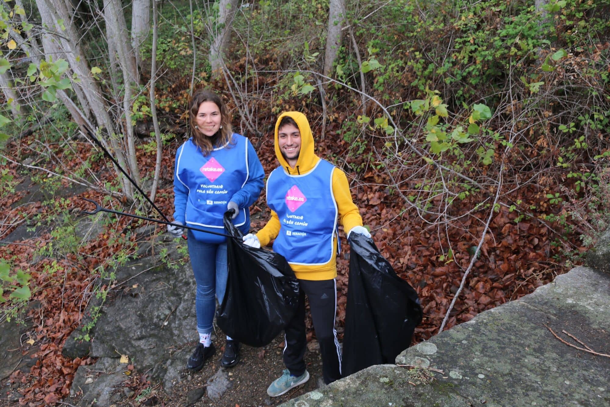 Dos voluntarios con chalecos azules entre árboles